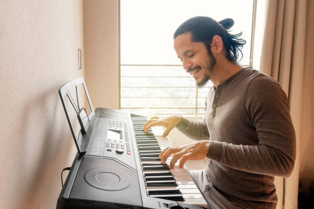 istock Young latin man smiling learning to play piano at home 1316467474