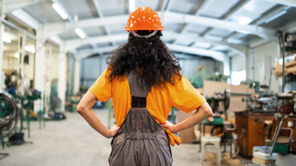 Female worker with helmet standing in a factory Female worker with helmet standing in a factory lean construction management stock pictures, royalty-free photos & images