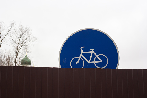 The sign indicating the bike road is one-third closed by a fence.
