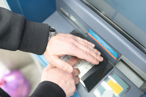 Close up shot of man depositing money on ATM