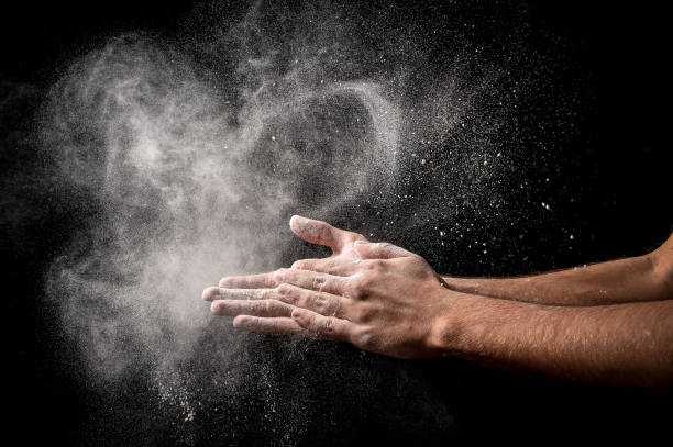 istock man chef hand claps with splash of white flour on black background 1316470067