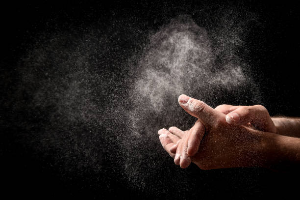 istock man chef hand claps with splash of white flour on black background 1316470097