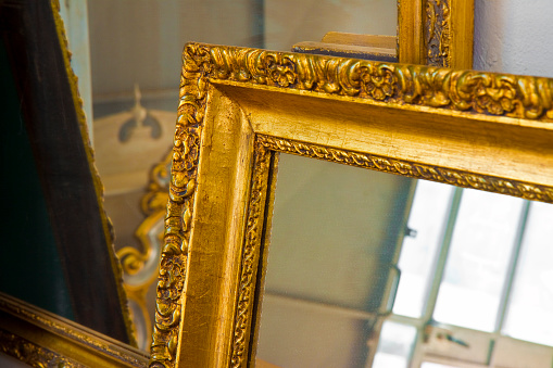 Detail of a carved and golden wooden frame with mirror