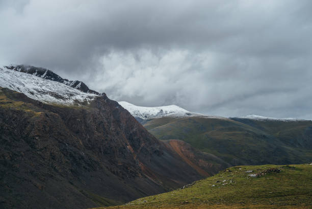 istock Atmospheric alpine landscape with deep gorge and snow-capped multicolor mountains in overcast weather. Beautiful scenery with snowbound mountain range under cloudy sky. Motley high mountains with snow 1316470429