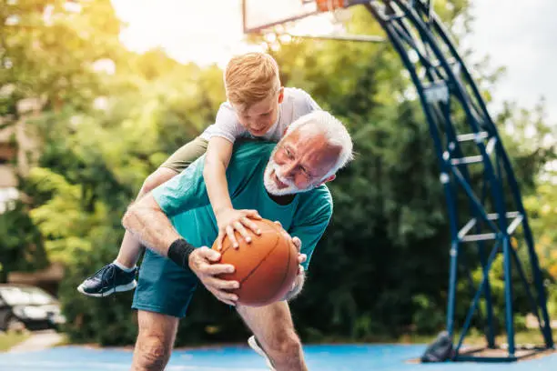 Photo of Grandfather and grandson on basketball court