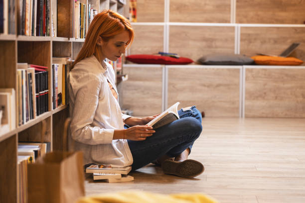 istock Young female student read and learns by the book shelf at the library.Reading a book. 1316474203