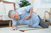 先輩男性が地面に倒れ、心臓発作による胸痛を伴う高齢のアジア人男性。