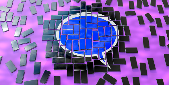 Many generic smartphones placed ad hoc on a flat plain purple surface, centrally concentrated with their displays formed a mosaic image of a speech bubble icon.