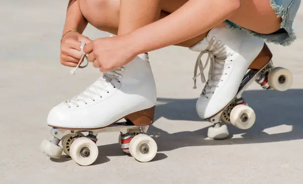 Close-up detail of skater's hands tying the laces of a roller skate