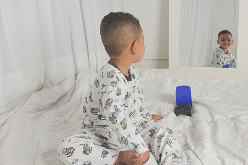 toddler boy in pajamas on bed