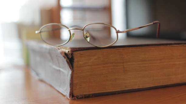 istock Glasses on Closed Vintage Book on the Library Table 1316480829