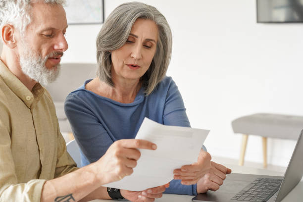 istock Older mature couple checking bank documents or bills using laptop at home. 1316483037