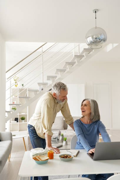 istock Happy middle aged couple using laptop computer and talking at home. 1316483055