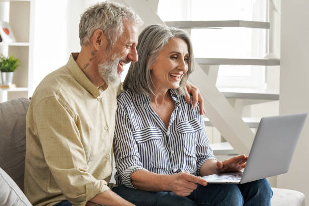 istock Happy older middle age couple using laptop looking at computer sitting on couch. 1316483060