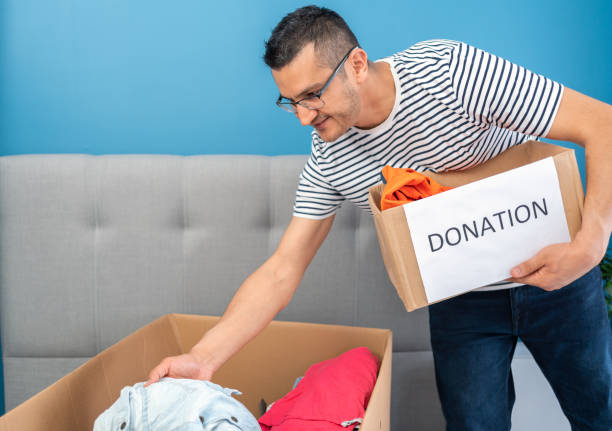 istock Man putting clothes into boxes for donations at home. 1316483283