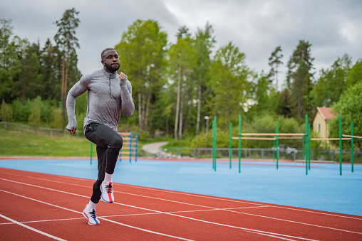 Young African American male athlete running on race track