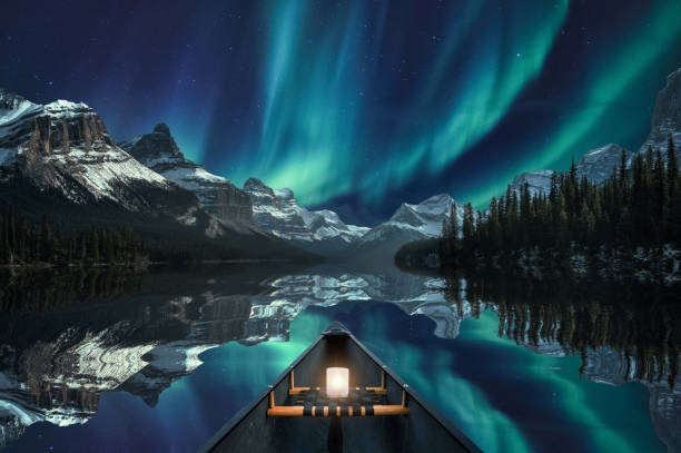 kanufahren mit aurora borealis über bergkette in maligne lake im jasper nationalpark - banff stock-fotos und bilder