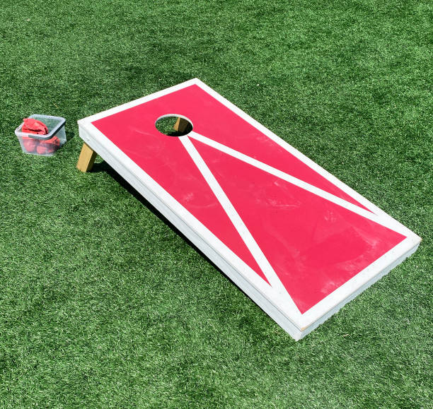 Red and white cornhole game board with bean bags to be thrown