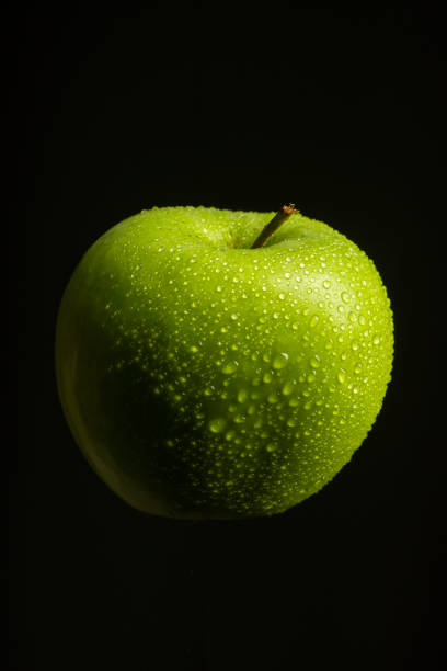 istock Green apple with water drops on black background 1316486403