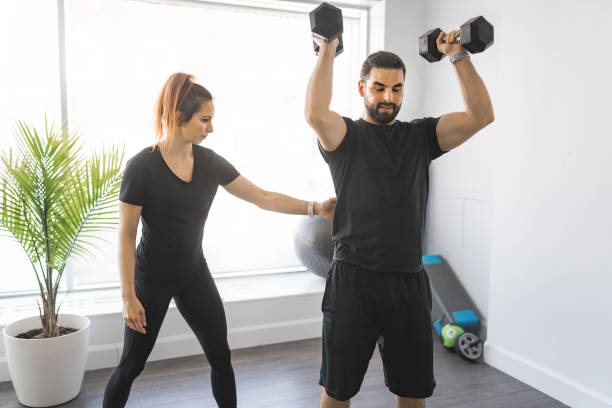 istock Trainer and client training with dumbbell at the gym 1316487807
