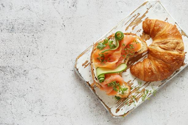 panino al croissant con salmone affumicato, cetriolo e micro verdure. - bun sandwich vegetable cream cheese foto e immagini stock
