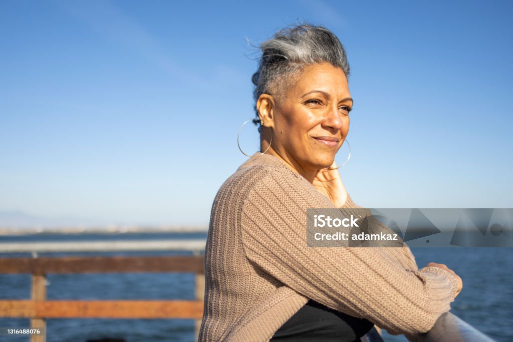 Mature black woman relaxing at the pier A mature black woman relaxes on the pier at the beach. One Woman Only Stock Photo