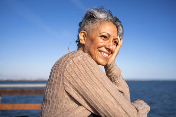 Mature black woman relaxing at the pier A mature black woman relaxes on the pier at the beach. grey hair stock pictures, royalty-free photos & images