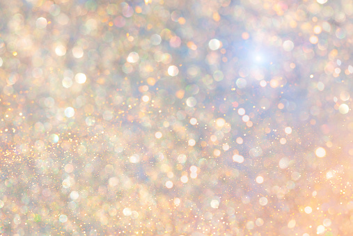 Rainbow background with shiny gold sequins. Glittering gold, festive light background.