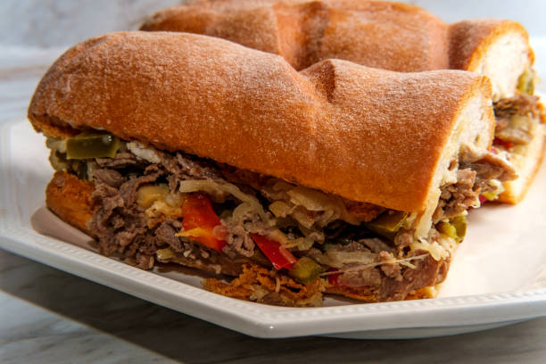 Messy Philly Cheesesteak Messy Philly cheesesteak with melted cheese mushrooms onions and peppers torpedo sandwich stock pictures, royalty-free photos & images
