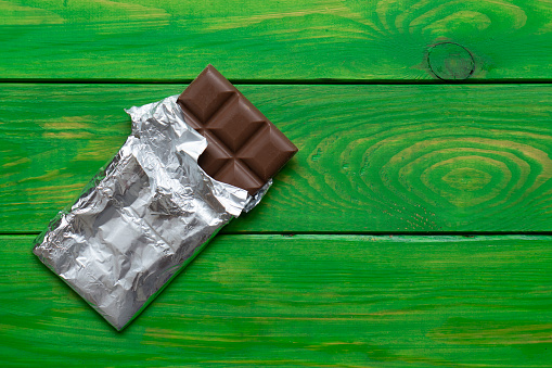 A bar of chocolate in foil wrapping on wooden