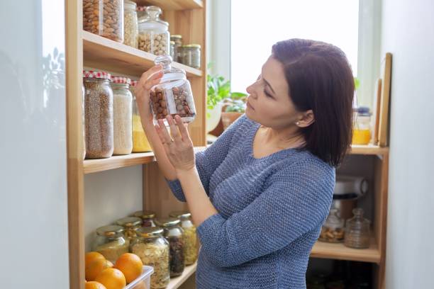 istock Home pantry kitchen interior, woman holding jar of hazel nuts 1316499233