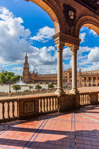 View from the arcade of Plaza de España in Seville framed in one of its arches. A spring day in Seville in vertical format.