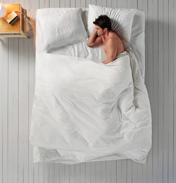 Sleeping in bed Overlooking a young man sleeping in comfy bed man sleeping top view stock pictures, royalty-free photos & images