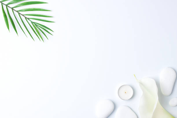 istock Spa background with white stones, candles, palm leaf and white flower on white. Flat lay,copy space 1316502872