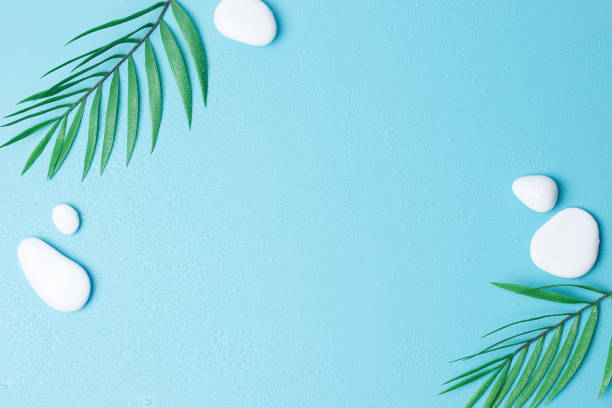 istock Spa background with white stones, water drops and palm leaves on blue. Flat lay,copy space 1316502883