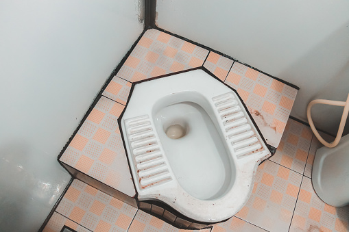 Traditional Vietnamese low white porcelain squat toilet in Vietnam, Southeast Asia.