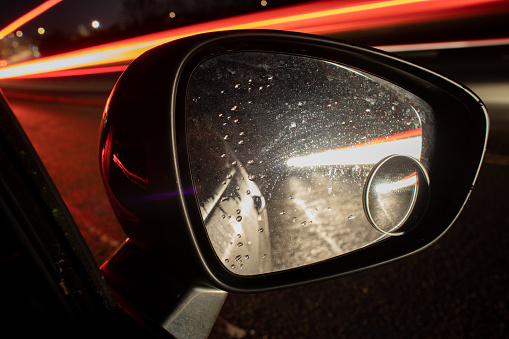 Headlights and tail light trails in a car wing mirror