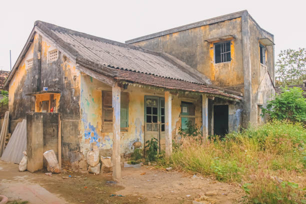 Old, neglected, decaying building with overgrown garden in rural village near Hoi An, Vietnam.
