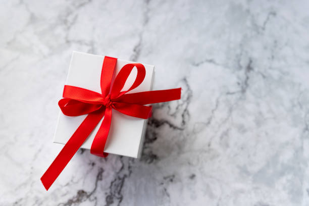 istock White gift box with red ribbon bow on marble background. holidays and celebration concept. copy space. present for celebrating Christmas, Valentine or an anniversary 1316506143