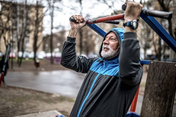 istock Sporty senior man doing pull-ups on cold rainy day. 1316508444