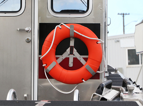 Orange life-saving kisby ring on boat, an orange life ring stock photo on a silver aluminum boat.