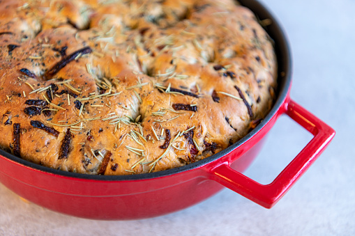 Fresh from the oven deep dish Italian focaccia bread baked in a large red cast iron skillet. Extreme close up.