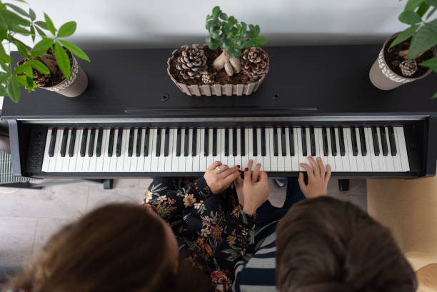 istock Mother and boy practicing piano at home 1316514335