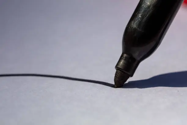 Close-up image of a black permanent marker writing on a white paper