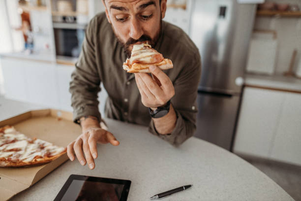 istock Man in the kitchen eating unhealthy food 1316520304