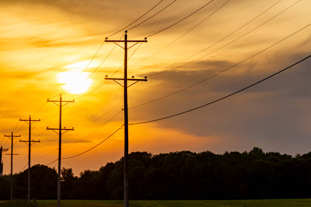 道路沿いの高圧電気を運ぶ電柱のシルエット - city of sunrise 写真 ストックフォトと画像