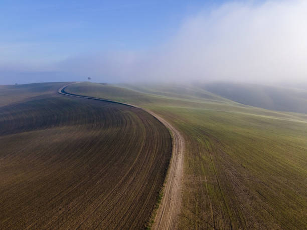 Aerial view of a dirt road in a misty morning fog in winter