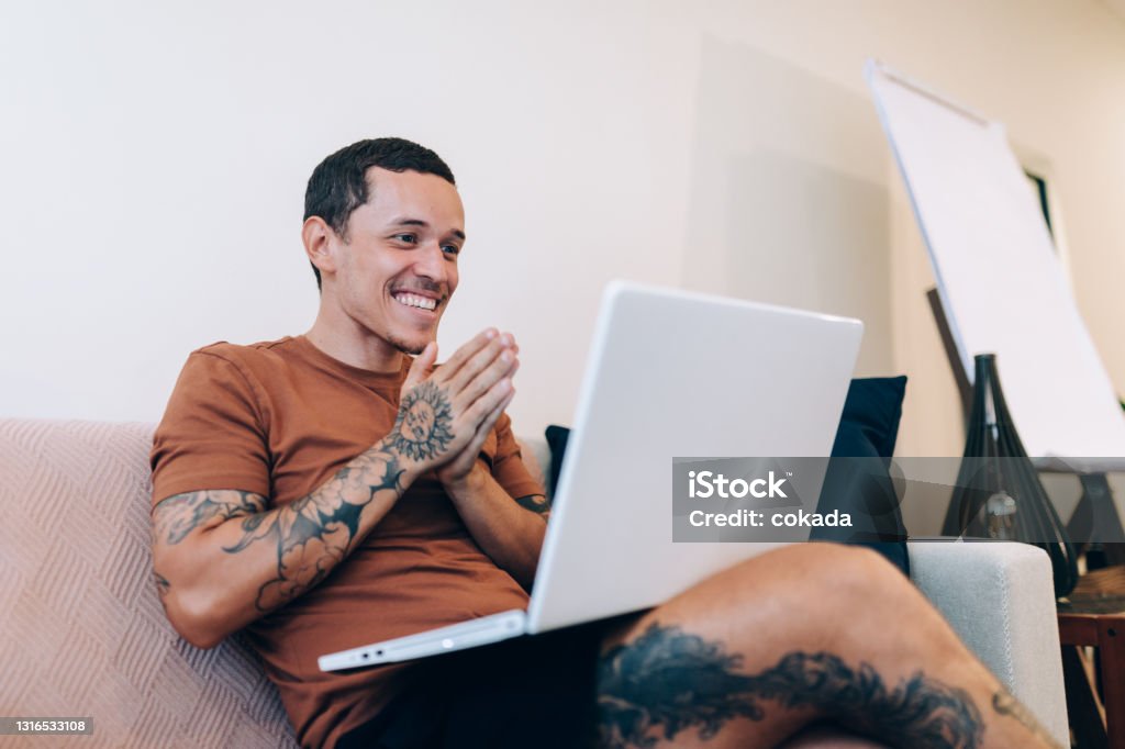 Happy young man using laptop at home Domestic Life Stock Photo