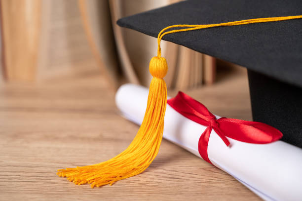 istock Graduation cap and Certificate diploma roll Paper on table in library 1316534960