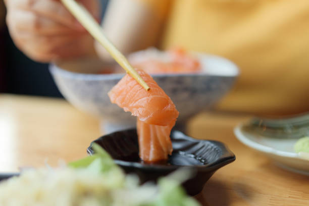 istock Salmon sashimi in chopsticks dipping with soy sauce 1316541678